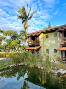 a house with a pond in front of it at Pousada Pacha Mama Village Bombinhas in Bombinhas