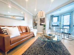 a living room with a brown couch and a glass table at Glasgow merchant city oasis in Glasgow