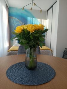 a vase of yellow roses sitting on a table at Apartament Maris Gdynia - Śródmieście - Klimatyzacja - Prywatny Parking in Gdynia