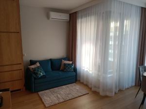 a blue couch in a living room with a window at Apartament Maris Gdynia - Śródmieście - Klimatyzacja - Prywatny Parking in Gdynia
