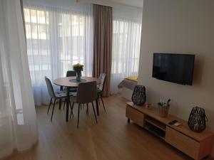 a living room with a table with chairs and a television at Apartament Maris Gdynia - Śródmieście - Klimatyzacja - Prywatny Parking in Gdynia