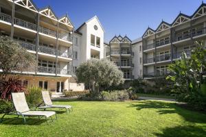 une rangée d'immeubles d'appartements avec des chaises dans une cour dans l'établissement Portsea Village Resort, à Portsea