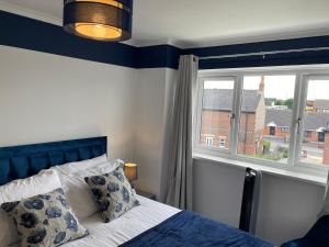 a bedroom with a bed with a blue headboard and a window at Stylish 3 bed house, private parking on premise, with conservatory, close to KFC, McDonalds, ALDI and ASDA in Sheffield