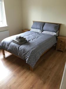 a bed with a blue comforter and a wooden floor at Mourne country cottage in Warrenpoint