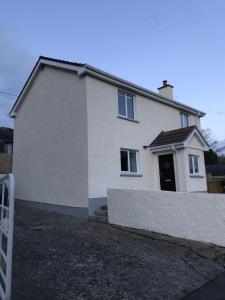 ein weißes Haus mit einem Zaun davor in der Unterkunft Mourne Country Cottage in Warrenpoint