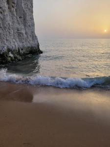 a beach with the sun setting over the ocean at Summer House at Percy Villas in Kent