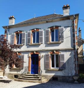 een wit huis met een blauwe deur en ramen bij villa l'Ambroisine in Lure