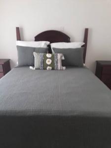 Una cama con sábanas grises y almohadas. en Tranquil 2 bedroom townhouse in Discovery Bay en Discovery Bay
