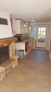 a large kitchen with white cabinets and a fireplace at Maisonnette 6 personnes en Auvergne à Saint Remy sur Durolle 