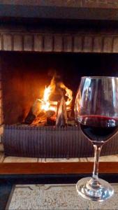 ein Glas Rotwein vor dem Kamin in der Unterkunft Casa Goldoni Gramado in Gramado