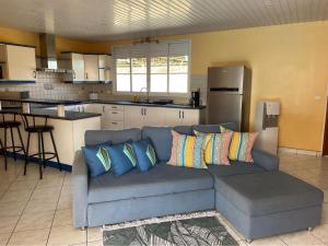 Una sala de estar con un sofá azul y una cocina. en TAHITI - Fare Vairai Pool, en Faaa
