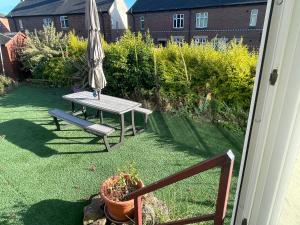 a patio with a table and an umbrella in a yard at Stylish 3 bed house, private parking on premise, with conservatory, close to KFC, McDonalds, ALDI and ASDA in Sheffield
