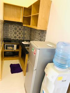 a small kitchen with a refrigerator with a lot of water at INDO Serviced Apartment in Ho Chi Minh City