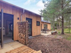 una cabaña de madera con una pila de leña al lado en 8 person holiday home in lb k en Ålbæk