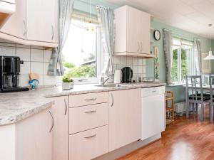 Holiday home Ebeltoft CXCIV في إيبلتوفت: مطبخ مع دواليب بيضاء وغرفة طعام