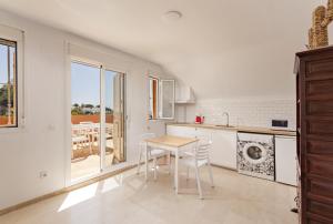 a white kitchen with a table and chairs in it at Fresh penthouse apartment with great sea views in Casares