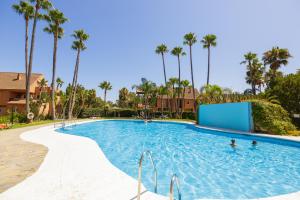 a swimming pool at a resort with palm trees at Fresh penthouse apartment with great sea views in Casares