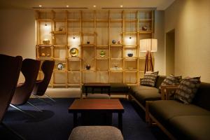 a living room with couches and tables and shelves at HOTEL AMANEK Kanazawa in Kanazawa