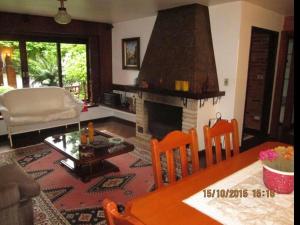 a living room with a fireplace and a table and chairs at CASA GOLDONI GRAMADO 4 Quartos in Gramado