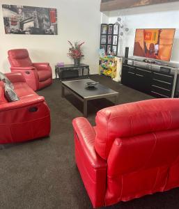a living room with red furniture and a flat screen tv at Kamo Studio Apartment in Whangarei