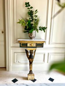 een console tafel met een vaas met bloemen erop bij Maison Loire in Blois