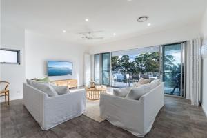a living room with two white couches and a table at Sunset Jewel - 7a Cromarty Road, Soldiers Point - Ocean Views, Breathtaking Sunsets, Linen, AIR CON & Wi-Fi in Soldiers Point
