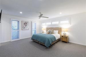 a white bedroom with a bed and two windows at Sunset Jewel - 7a Cromarty Road, Soldiers Point - Ocean Views, Breathtaking Sunsets, Linen, AIR CON & Wi-Fi in Soldiers Point