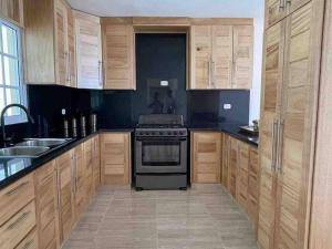 uma cozinha com armários de madeira e um fogão em Casa Familiar en el Valle de Constanza em Constanza