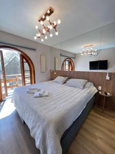 a bedroom with a large bed with two towels on it at Flat da Babi, MODERNO, LUXUOSO, EQUIPADO e 600mb wifi in Campos do Jordão