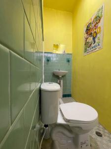 a bathroom with a white toilet and a yellow wall at La Palmera Hostel in Cali +83 photos