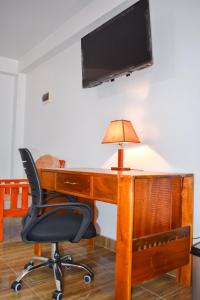 a desk with a chair and a television on a wall at CASA TALIOS in Carhuaz