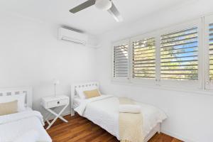 a white room with two beds and a window at Stylish Townhouse, private courtyard walk to beach in Noosaville