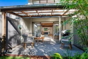 an outdoor patio with a pergola and chairs at Stylish Townhouse, private courtyard walk to beach in Noosaville