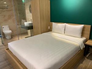 Un dormitorio con una gran cama blanca y un baño. en LÁ HOTEL RIVERSIDE, en Ho Chi Minh