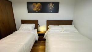 duas camas sentadas uma ao lado da outra num quarto em REPUBLICANA CASA HOSTAL - HABITACIÓN 6 CALIMA em Bogotá
