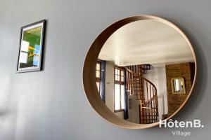 a round mirror hanging on a wall with a staircase at T3 Duplex charme de l'ancien - coeur de ville in Limoges