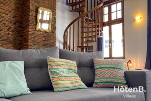 a gray couch with pillows sitting in a living room at T3 Duplex charme de l'ancien - coeur de ville in Limoges +26 photos