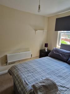a bedroom with a bed with a blue blanket and a window at Maidstone Heights III - 1 bedroom in Maidstone! in Maidstone