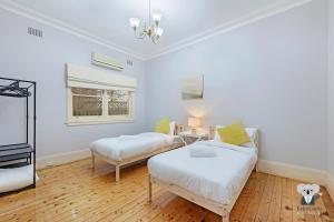 a bedroom with two beds and a tv in it at KOZYGURU Campsie Oldie-but-goodie look 4 Bed House NCA011 in Sydney +2 photos