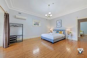 a large bedroom with a bed and a wooden floor at KOZYGURU Campsie Oldie-but-goodie look 4 Bed House NCA011 in Sydney