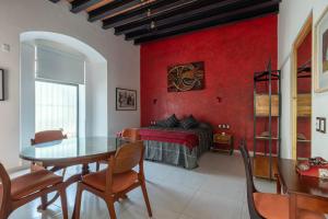 a living room with a table and a red wall at LARIMAR Gallery y Hotel Boutique in Oaxaca City