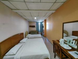 a room with two beds and a table and a mirror at Century Hotel Inanam in Kota Kinabalu