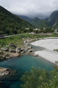 景美村的住宿－花蓮三棧頌月民宿，一条有蓝色水和岩石及山脉的河流