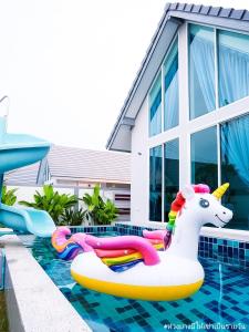 una piscina con una balsa inflable unicornio y una casa en Be19th Pool Villa, en Cha Am