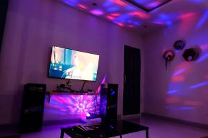sala de estar con TV y luces púrpuras en Be19th Pool Villa, en Cha Am