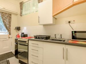 a kitchen with white cabinets and a stove top oven at Clooneavin Chalet in Lynmouth