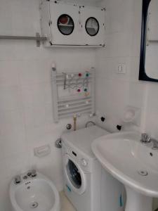 baño blanco con lavadora y lavamanos en Trilocale in dimora tipica, en Montale