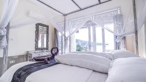 1 dormitorio con cama con dosel y ventana en Waenis Sunset View Hotel and Restaurant, Amed, Bali, en Amed