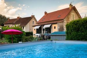 a house with a swimming pool and a pink umbrella at Chambres d'hôtes Ecole Buissonnière en Dordogne in Le Buisson de Cadouin