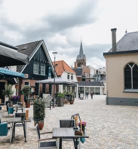 une place de ville avec des tables et des chaises ainsi qu'une église dans l'établissement Stadshotel Rijssen, à Rijssen
